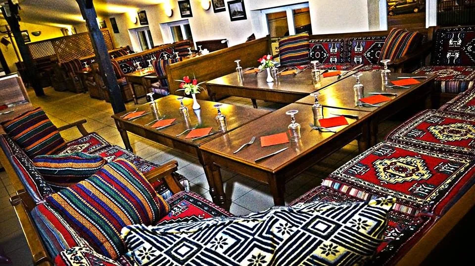 La salle de Chark : banquettes en kilims, tables en bois, fleurs rouges